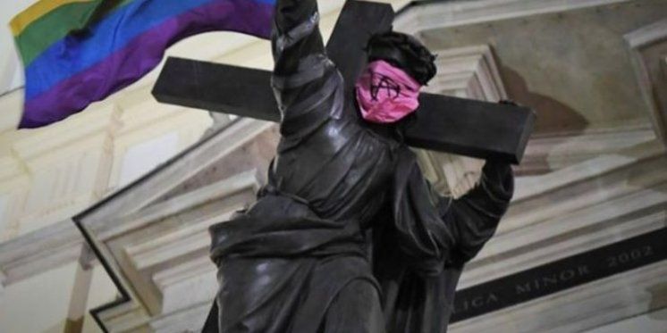 Kip Isusa oskrnavljen LGBT duginom zastavom i anarhističkom simbolom